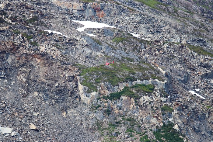 A helicopter perches in the middle of bedrock fragmented by its slow creep toward the retreating Portage Glacier.
