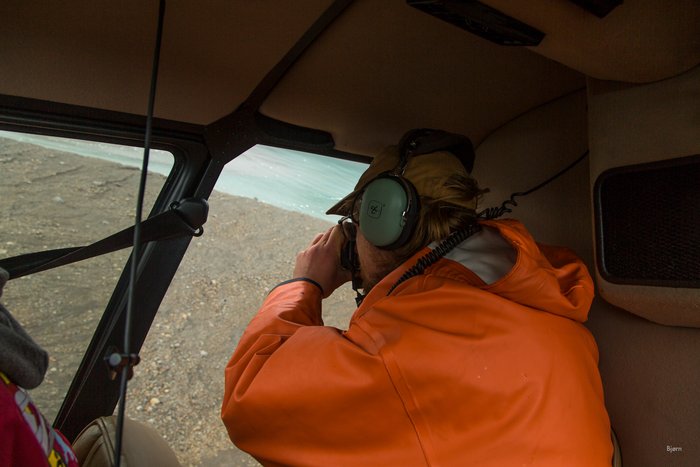 Dr. Bretwood Higman photographs the landslide debris, on Hoof Hill Fan, out of a door-less helicopter. 