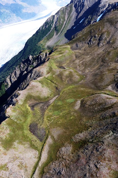 A dry pond appears to have cracks in it, running parallel to nearby cliffs.