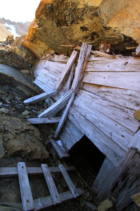 As a kid I followed this route into the mine once.  The ladder descends into darkness down a irregular shaft.  Rotten steps near the top are followed by stronger wood below where cold still air has preserved them.