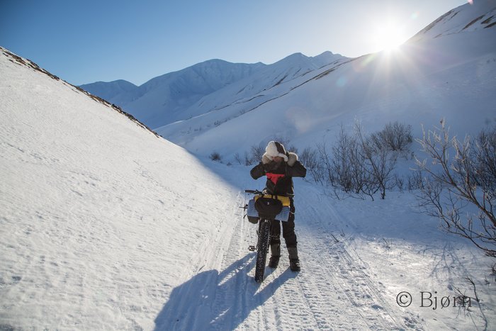 Riding out of the shadows and into the sunlight near the summit of Rainy Pass.