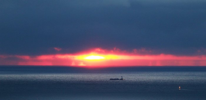 Sunset light iluminates lower Cook Inlet, where a small shipping vessel and an even smaller fishing boat head south.