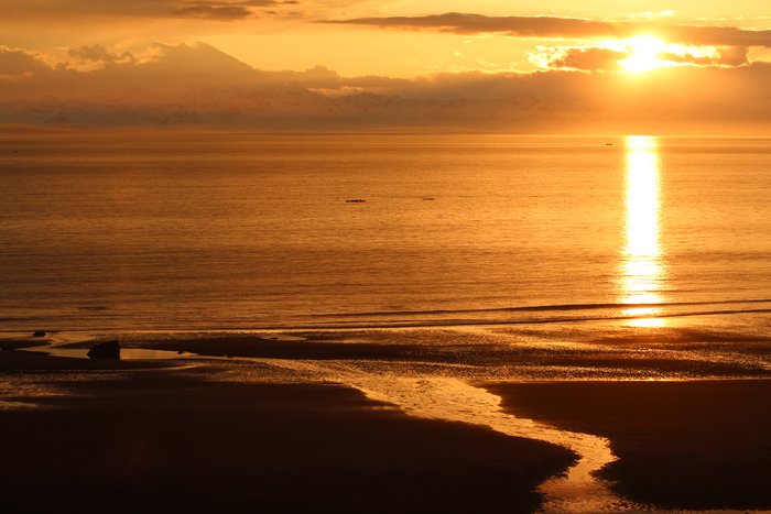 The sun sets next to Redoubt Volcano.