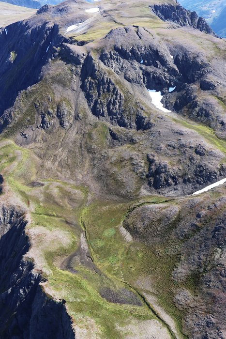 Fissures bisect the peak and slopes of this mountain above a lake and retreating glacier in Alaska.
