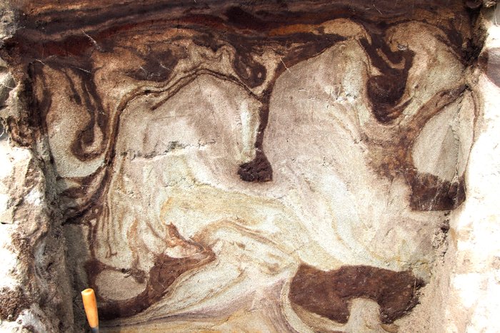 Ice in soil does bizarre things given long enough.  These plumes and blobs of soil in sand are the result of "cryoturbation" - the result of freeze-thaw cycles over many centuries.