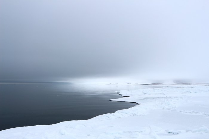 Ice reflects light, brightening the sky. Over the water, the sky is dark.