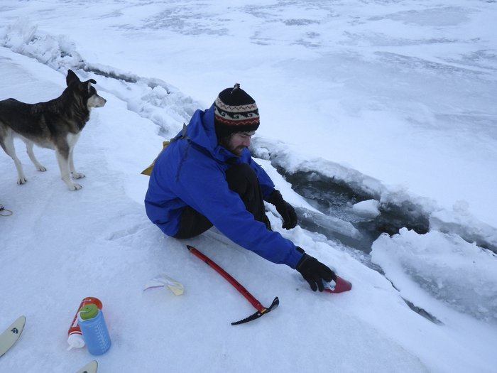 Caleb pauses to fill water bottles in a crack created by a pressure ridge in Lake Iliamna
