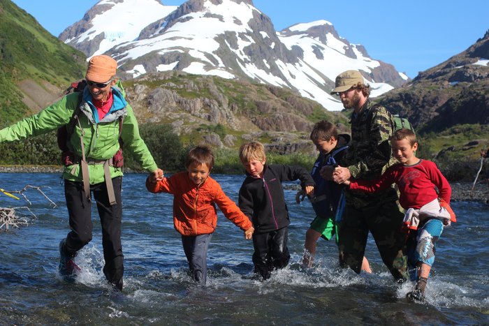 Kids and adults hold hands to cross one of the channels in upper Tutka valley