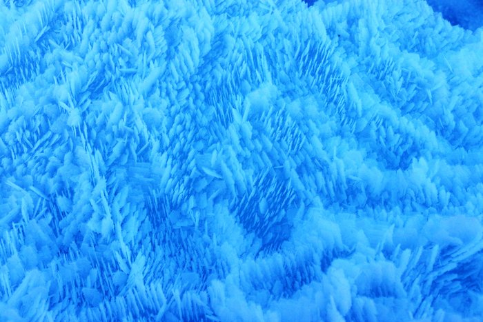 Aligned frost crystals texture a huge berg protruding out of lake ice on Grewingk Lake.