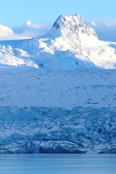 Snowy peaks protrude into the sun above shadowed Grewingk Glacier.