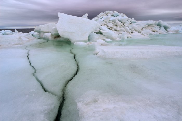 Sea ice, broken and piled, melting in the wind and rain.