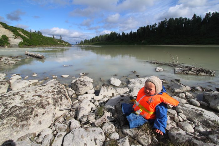 Katmai sits on the edge of the Beluga River, waiting for his packraft ride.