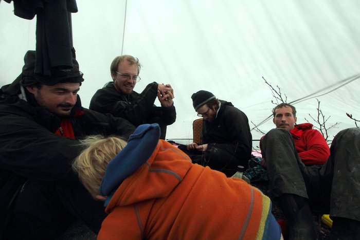 2 kids and 7 adults, weathering driving rain by the fire in our Titanium Goat tent.