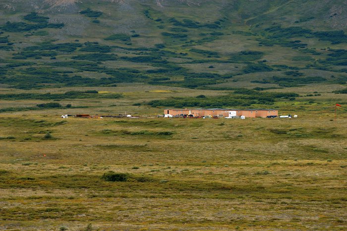 A base camp for mining reconnaissance at the bottom of the hill containing the mineral deposit.