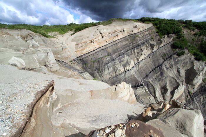 A flash of sun on a cloudy day illuminates dramatic sandstone bluffs near Gold Run Pass mine.