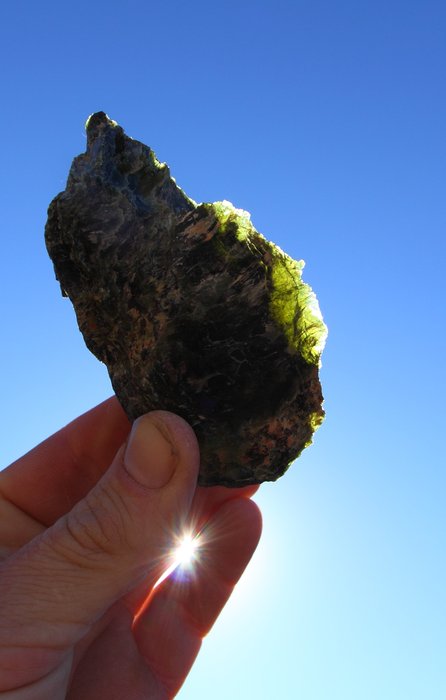 A transparent green, yellow, or gray mineral that forms when olivine reacts with water.