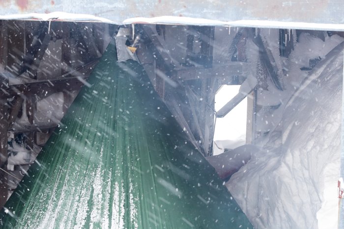 A mining building, likely a repair shop of some sort, provides a place to shelter from the wind in Tin City.