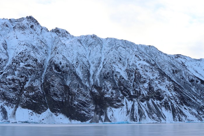 Steep slopes extending above the gleaming ice of Grewingk Lake