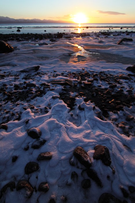 Ice on the beach, sun on the horizon.
