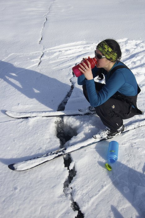 Kate stopping to sip some water from a crack created by a pressure ridge in Lake Iliamna 