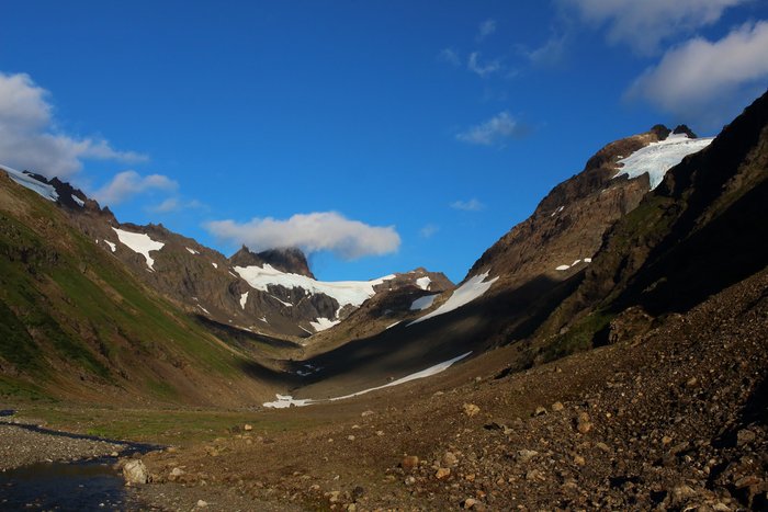 Hanging glaciers on the mountains along Tutka Pass are retreating, and have recently moved out of the high point of the pass.