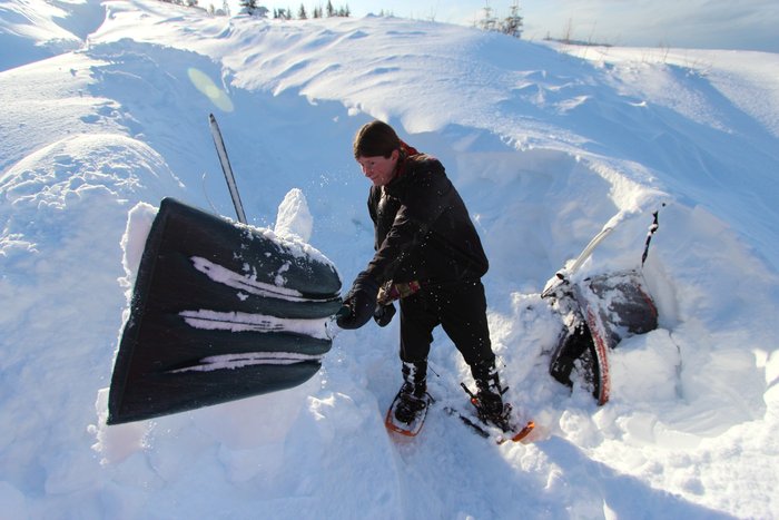 With a sleeping baby on her back, Erin shovels out the bike and trailer from under a 6 foot snow drift.