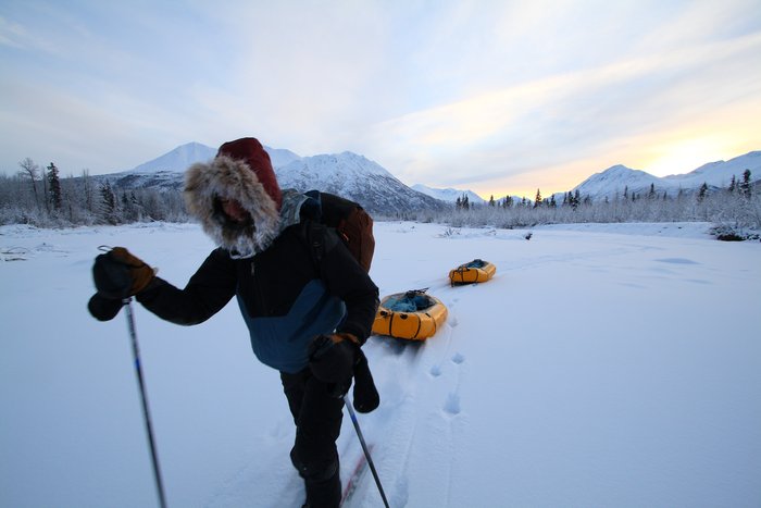 A frosty ruff lines Hig's modified coat, packrafts trailing behind as makeshift sleds. 