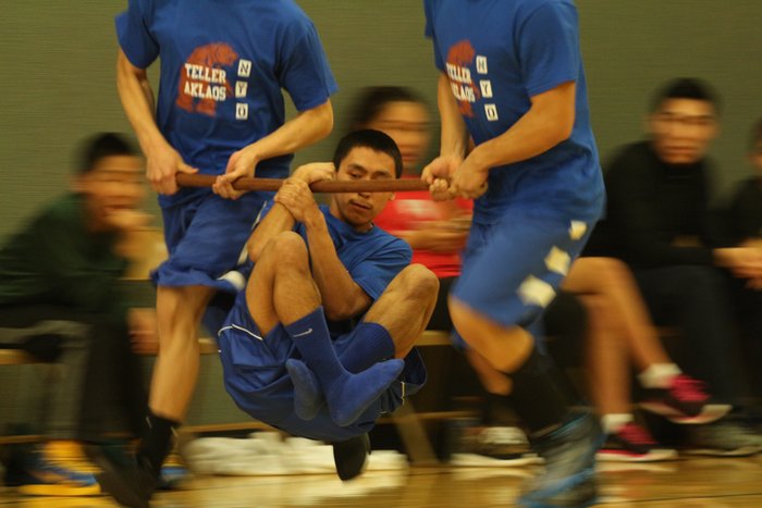 Two team mates carry you while you hold yourself to a wooden pole by a kinked wrist.  Most fall in seconds, but this kid made it twice around the gym.